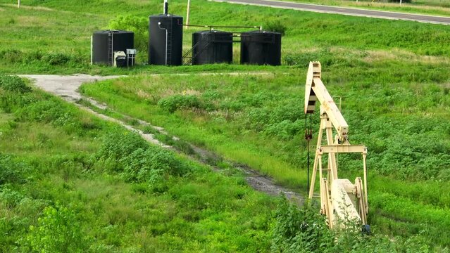 Crude oil well. Aerial shot of holding tanks for storage of pumped oil, and an oil well pumping petroleum out of rural ground in USA.