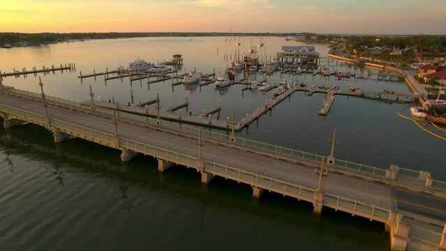 Aerial video on a golden sunrise in Saint Augustine, FL over the Matanzas River. The Lions Bridge stretches along the calm waters and the boats sit along the quite docks.