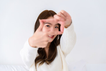 Young asian woman happy and making frame with fingers on white background in house