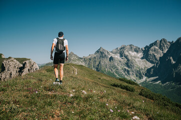 Captured in action, a youthful trekker explores the emerald ridge of the Belianske Tatras, offering a captivating view of the towering High Tatras in the distance