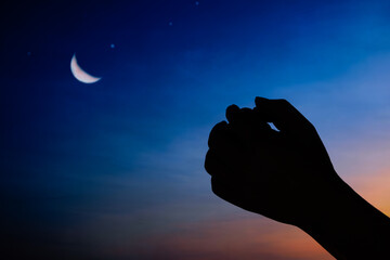 Hands of an Islamic man asking for blessings from the gods. Background with half moon and starry sky. The ray of hope holds an important place in Islam.