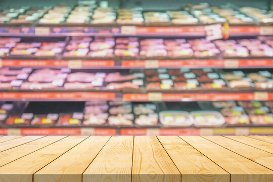 Empty wood table top with blur meat shelves in supermarket background for product display