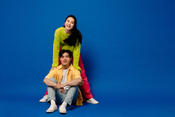 Young asian couple posing isolated over blue background