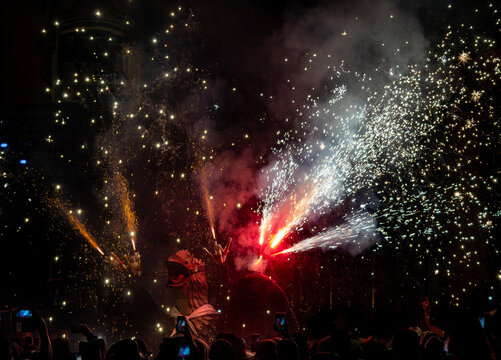 Mythical dragon dancing in a pyrotechnic show with fireworks shooting from its head during the traditional festival. People record with their mobile phones.