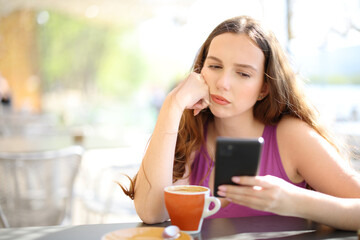 Frustrated woman checking phone in a restaurant