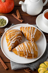 Traditional pumpkin scones with cinnamon, anise and sugar glaze on top. Autumn dessert.