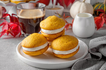 Pumpkin sandwich cookies with cream cheese on a gray concrete bsckground. Spicy autumn dessert. Copy space.