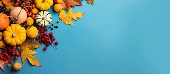 Foto op Canvas Thanksgiving scene with fall foliage pumpkins and berries against a blue backdrop © vxnaghiyev