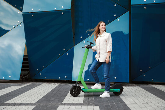 Happy woman with modern electric kick scooter on city street, space for text - Powered by Adobe