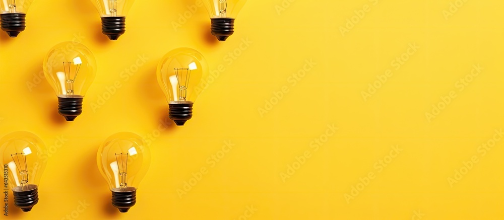 Poster top view of light bulbs arranged on a yellow background with copy space symbolizing ideas inspiratio