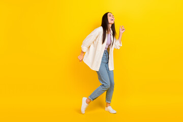 Fototapeta na wymiar Full size photo of adorable funky positive girl wear white shirt denim trousers dancing having fun isolated on yellow color background