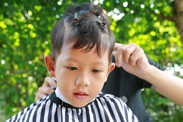 Asian boy cut in hairdresser's machine in the garden
