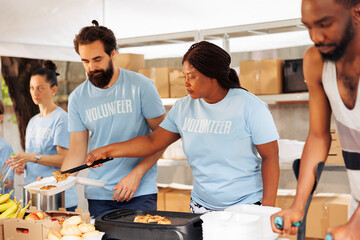 Multiethnic volunteers providing humanitarian aid, donating essential items and cooking for the...