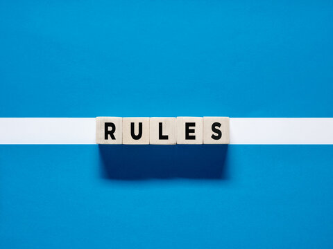The word Rules on wooden cubes on blue white background.