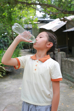 Thirsty Asian girl drink water from plastic bottle in the garden.