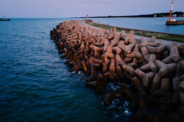 Waves break on concrete tetrapod breakwaters at sea coast. Protection from large waves. Baltic Sea...
