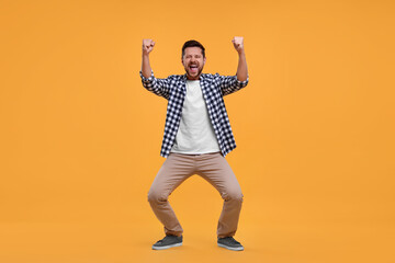 Emotional sports fan celebrating on yellow background