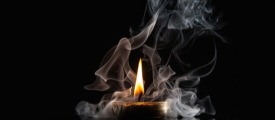 Extinguished candle with smoke rising on black background symbolizing completeness
