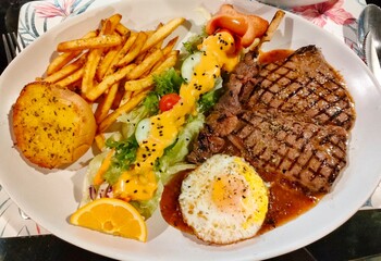 presented steak dish is a feast for the eyes and the taste buds. The star of the plate is a perfectly cooked steak, seared to a mouthwatering medium-rare perfection. Its exterior is gorgeously caramel