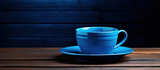 Matching dish and blue cup of coffee on black wooden background