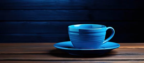 Zelfklevend Fotobehang Koffie Matching dish and blue cup of coffee on black wooden background