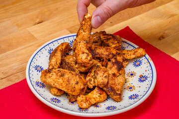 Usmażone kawałki kurczaka na talerzu i w dłoni 