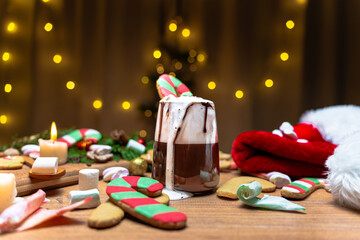 Gingerbread candy cane in a cup of hot chocolate with whipped cream, Christmas interior. red hat Santa