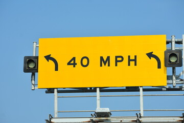 40 mph speed limit sign stands against a clear, sunny sky in an urban area