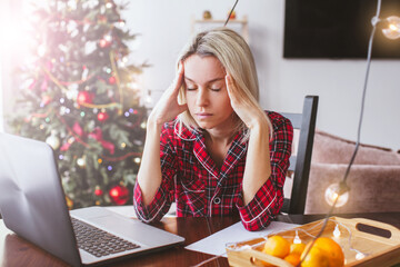 Sad middle aged woman working at the home office by laptop during Christmas holiday - 643531956