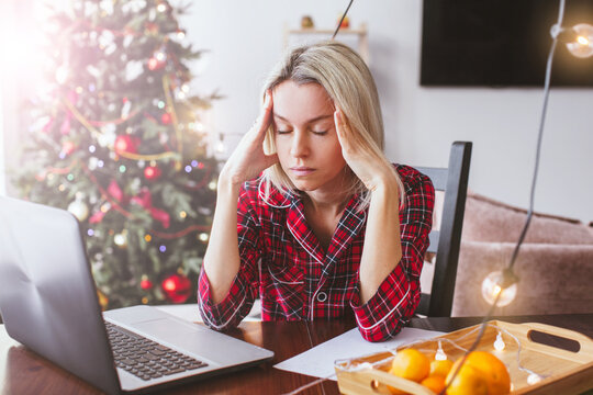 Sad middle aged woman working at the home office by laptop during Christmas holiday