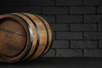 One wooden barrel on table near brick wall, closeup. Space for text