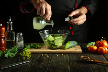 The chef prepares a salad on the kitchen table for a vegetarian lunch. Add lemon juice to cucumber and tomato salad