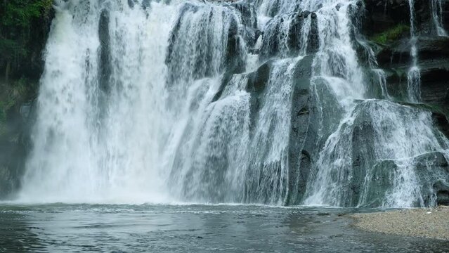 A waterfall cascades in a tropical rainforest with rock.