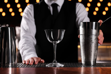 Bartender with shaker and glass in bar, closeup. Preparing alcoholic cocktail