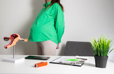 Pregnant girl in a green blouse in the office of an obstetrician gynecologist. The concept of...