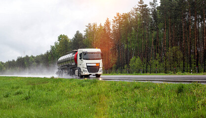 A truck with a semi-trailer tanker transports a dangerous cargo of fuel on a motorway slippery in...