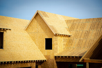 L shaped wooden house with gabled dormer roof under construction, oriented strand board (OSB) plywood sheeting envelope in suburbs Atlanta, Georgia, USA