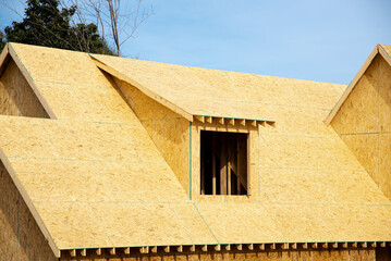 Gabled dormer roof with oriented strand board (OSB) plywood sheeting ridge edge envelope in...