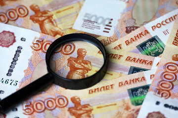Russian rubles and magnifying glass, paper currency. Concept of economy of Russia, exchange rate