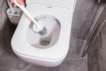 Modern silicone brush for cleaning the dirt of the wall-mounted toilet. Toilet care and hygiene concept, close-up