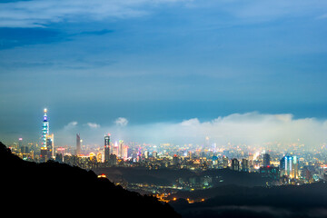 Nighttime Vista: Captivating City Lights and the Playful Dance of Clouds. View of the urban landscape from Dajianshan Mountain, New Taipei City, Taiwan.