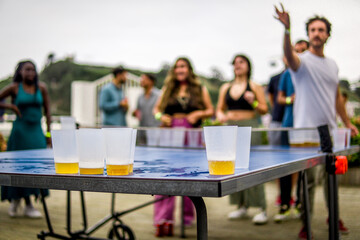 Guy Making the Gesture of Throwing the Ball into the Rival's Cups in a Beer Pong Game During a Friends Party in the Backyard - obrazy, fototapety, plakaty