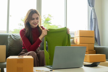 Small business start-up, SME owner, female entrepreneur working on receipt boxes with laptop and...