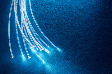 Bundle of optical fibers with lights in the ends. Blue background.