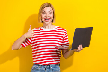 Photo of charming cheerful girl wear trendy clothes hand hold macbook nice feedback isolated on yellow color background