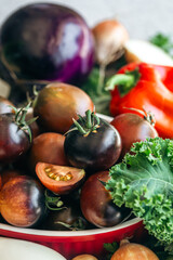 Close-up, bowl with ripe black tomatoes on the kitchen table.