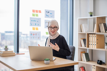 Arabian lady hosting web conference via laptop in workplace