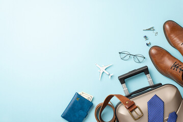 Executive's overseas journey setup. Top view mini plane model, formal accessories – belt, silk tie, leather shoes, suitcase, document holder, tie clip, cufflinks, purse on soft blue with room for text