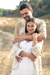 Mature man and woman in the field are hugging.
