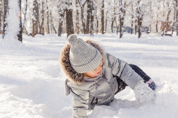 Fototapeta premium Little girl playing with snow in the winter park. Winter activities for children.